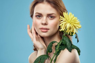 Yüzüne yakın sarı çiçekli güzel bir kadın. Çıplak omuzların kırpık manzaralı portresi.