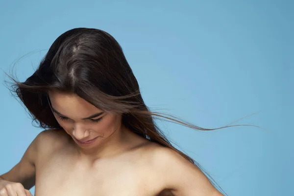 Brunetta con spalle nude cosmetici close-up cura della pelle sfondo blu — Foto Stock