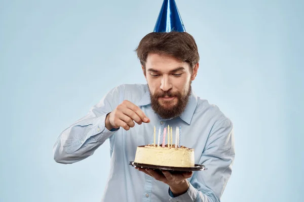Torta egy tányéron és szülinapos férfi sapkával a fején kék backgroun — Stock Fotó