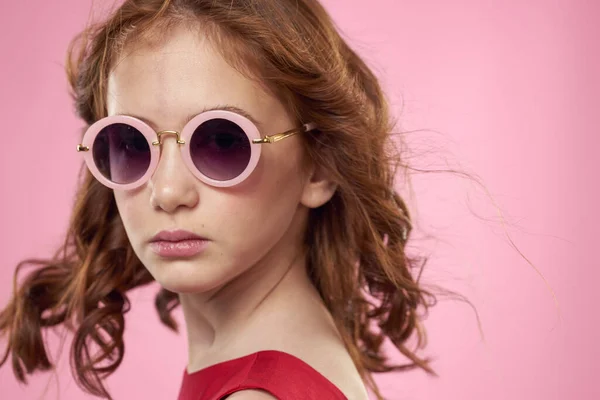 Chica con pelo rizado gafas de sol alegría infantil fondo rosa — Foto de Stock