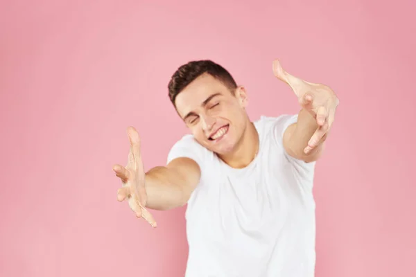 Emocional hombre gesto con sus manos blanco camiseta rosa aislado fondo —  Fotos de Stock