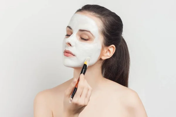 Mujer bonita con hombros desnudos está en la mano aplicando cosméticos cuidado de la piel —  Fotos de Stock