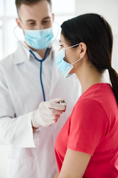 의사가 마스크를 쓰고 보호 장갑을 끼고 목에 청진기를 두르고 있는 환자의 진찰을 받고 있는 모습 — 스톡 사진