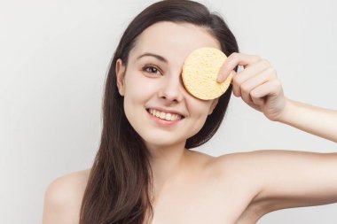 Yüzündeki makyajı silmek için omuzları açık esmer bir kadın.