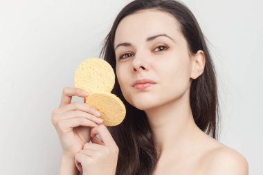 Yüzündeki makyajı silmek için omuzları açık esmer bir kadın.