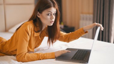 Kadın dizüstü bilgisayarın önünde uzanıyor. İnternet iletişimi dinleniyor.