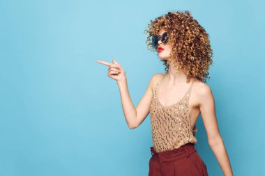 Seksi model kıvırcık saçlar Stüdyo Kopyalama Uzayı parlak makyajına parmağını gösteriyor