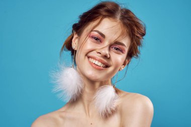 Neşeli kadın çıplak omuzlar tüylü küpeler saf deri mavi arka plan.