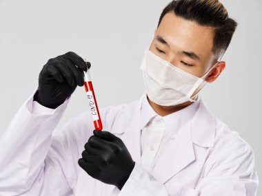 Siyah eldivenli bir Asyalı teşhis testlerine bakıyor.
