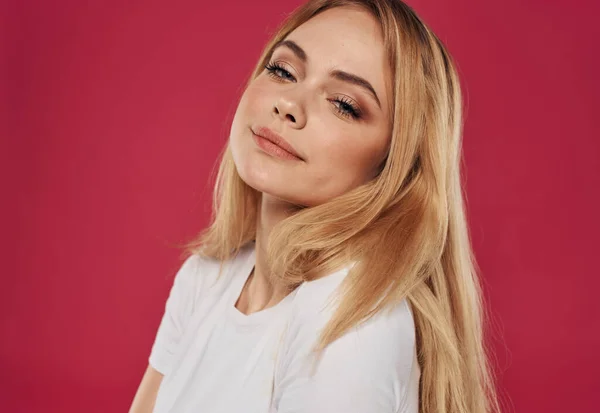 Porträt einer schönen Blondine in einem weißen T-Shirt auf rotem Hintergrund. — Stockfoto