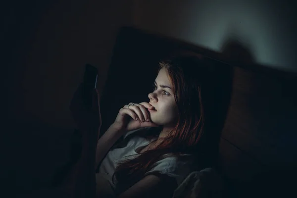 Vrouw met een telefoon in haar handen ligt in bed 's nachts voordat naar bed technologie — Stockfoto