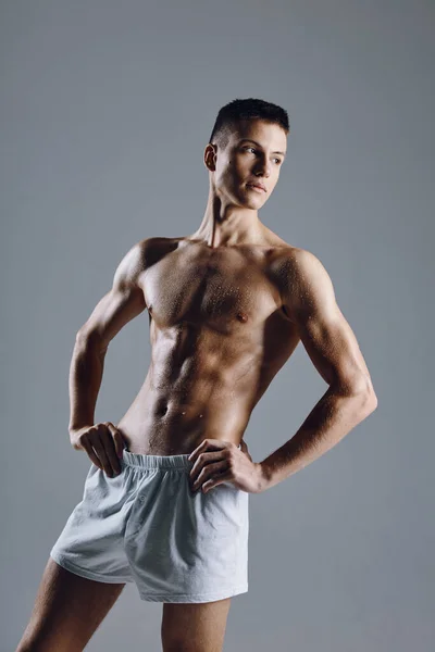 Silný samec sportovec s ohnutými pažemi svaly na šedém pozadí — Stock fotografie