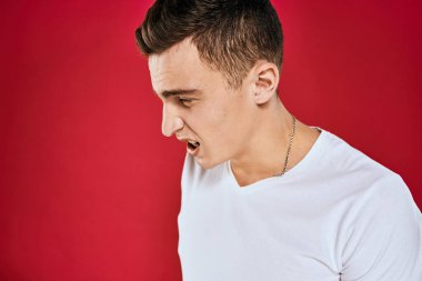 Duygusal erkek beyaz tişörtü hoşnutsuz yüz ifadesi kırmızı izole edilmiş arka plan görünümü