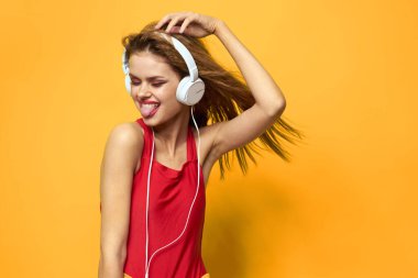 Beyaz kulaklıklı duygusal kadın müzik dinliyor. Eğlenceli yaşam tarzı sarı arka plan.