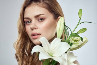 Çiçeklerle süslenmiş kız portresi. Kapalı yay, çıplak omuzlar. Makyaj.