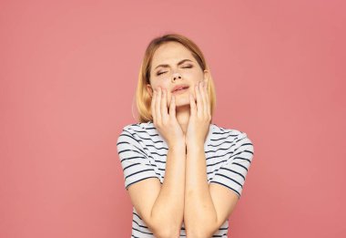 Güzel sarışın ellerini pembe bir arka plan modelinin üzerinde gezdiriyor.