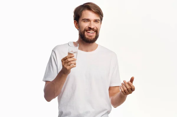 Gioioso uomo con un bicchiere d'acqua bianco t-shirt sfondo chiaro — Foto Stock