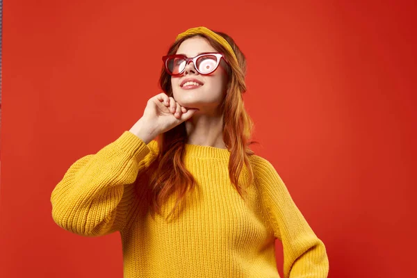 Mulher bonita em suéter amarelo óculos vermelhos roupas da moda close-up fundo vermelho — Fotografia de Stock