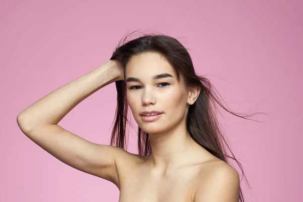 woman with bare shoulders clear skin body care pink background