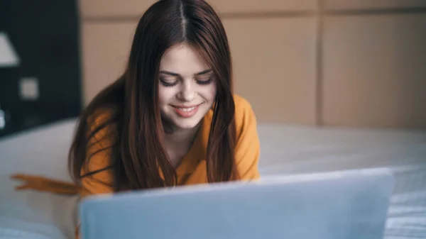 Mulher alegre encontra-se na cama na frente de laptop internet férias — Fotografia de Stock