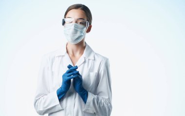 Tıbbi maskeli bir kadın laboratuvar asistanı. Şişede kimyasal bir madde var.