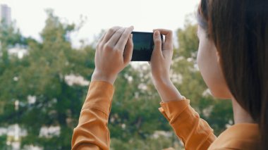Doğada elinde telefon olan bir kadın doğanın resimlerini çekiyor.