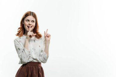 Takım elbiseli güzel, kızıl saçlı bir kadın parmak işareti yapıyor. Kopyalama alanı izole edilmiş arka plan.