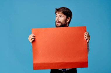 Kırmızı pankart taşıyan neşeli sakallı adam mavi arka plan stüdyosu