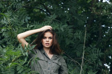 Kadın dışarıda elini başının üstünde tutuyor. Güzel bir yüzü var. Temiz hava.