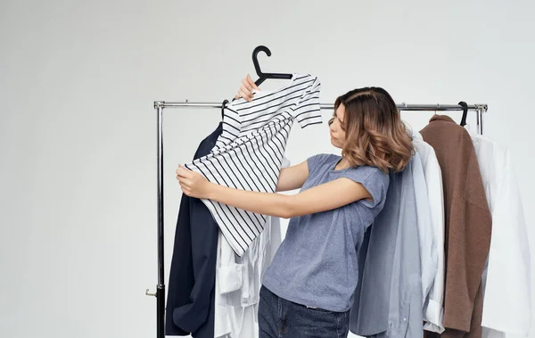 Žena zkoumá pruhované tričko v blízkosti oblečení v šatníku nakupování — Stock fotografie