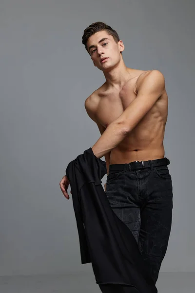 Bonito hombre con una chaqueta negra en topless en las manos de un estudio de glamour — Foto de Stock