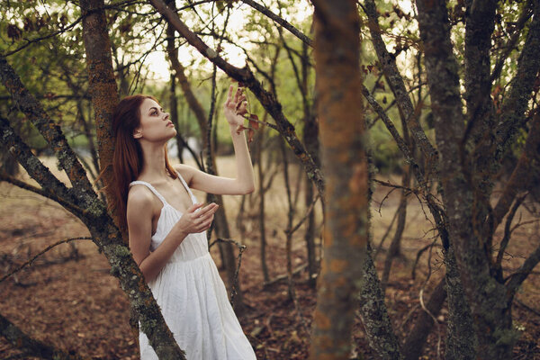 Sexy woman in white summer dress near trees in the garden. High quality photo