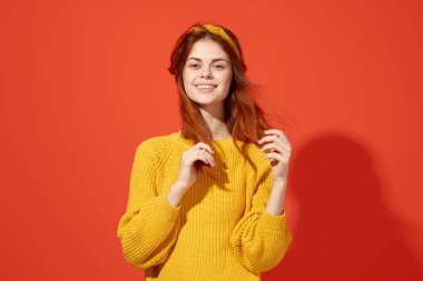 Sarı süveterli, kızıl saçlı, sevimli bir kadın.