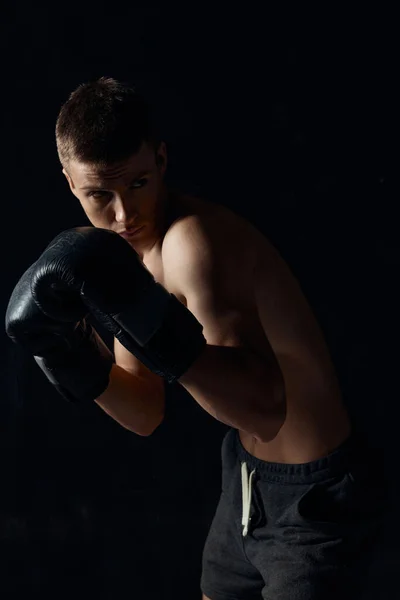 Boxer v černých rukavicích ohnutý na tmavém pozadí kulturista — Stock fotografie