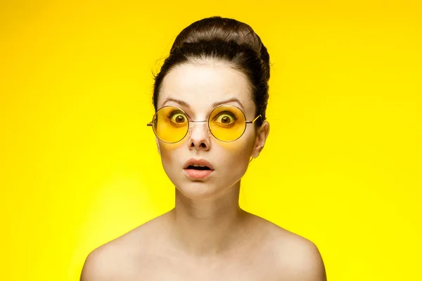 Güzel kadın, eğlenceli sarı gözlükler, çıplak omuzlar. — Stok fotoğraf