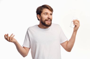 Bir bardak su ve beyaz tişörtle neşeli bir adam. Arka planda hafif arka planda, elleriyle el kol hareketi yapıyor.