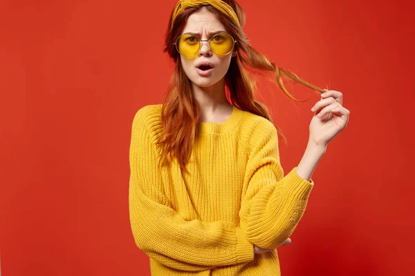 Bonita mujer en suéter amarillo sosteniendo el pelo emociones recortadas ver fondo rojo — Foto de Stock
