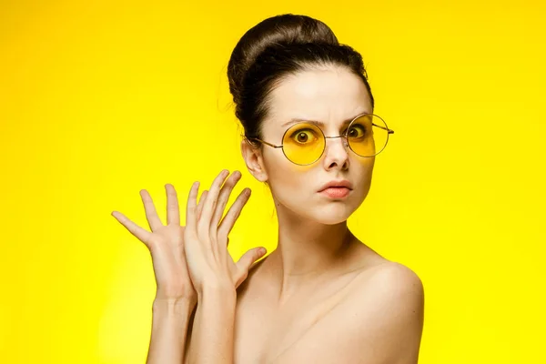 Çıplak omuzlu, açık tenli, sarı gözlüklü, el hareketli bir kadın. — Stok fotoğraf