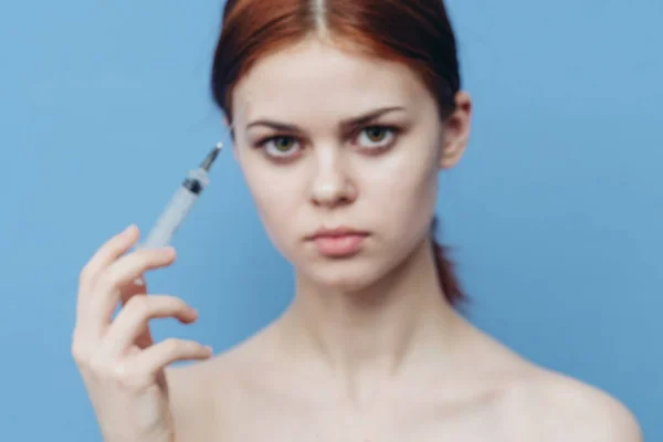 Mulher segurando seringa perto de cara botox rejuvenescimento injeção fundo azul — Fotografia de Stock