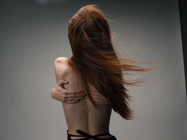 Обнажённая женщина прикасается к себе за спиной стрессовыми эмоциями рук, рыжие волосы — стоковое фото
