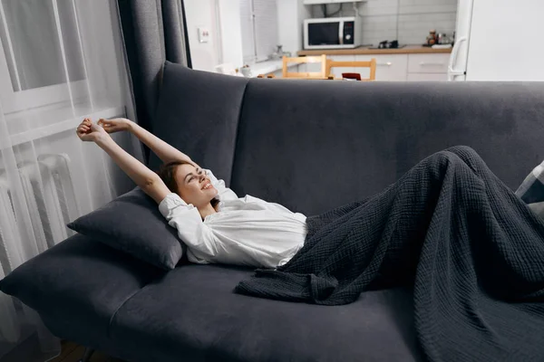 Szczęśliwa kobieta z podniesionymi ramionami leży na kanapie — Zdjęcie stockowe