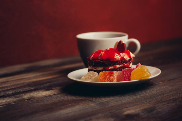 Round red cake on a plate marmalade sweets dessert wooden table