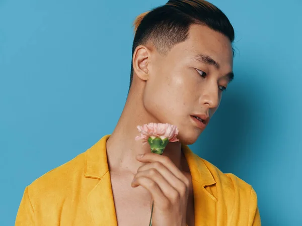 Jóképű ázsiai férfi virág romantika kék háttér sárga kabát — Stock Fotó