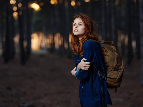 Kobieta z plecakiem i niebieską koszulą w pobliżu drzew w lesie uśmiechnięta modelka — Zdjęcie stockowe