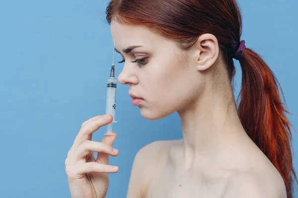 Mujer sosteniendo la jeringa cerca de la cara botox rejuvenecimiento inyección fondo azul — Foto de Stock