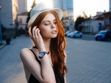 Beyaz şapkalı, siyah elbiseli, kırmızı saçlı güzel bir kadın.