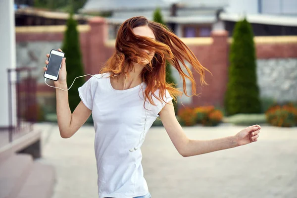 Mujer bonita al aire libre caminando por la calle con tecnología de auriculares — Foto de Stock