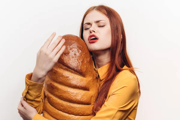 A cheerful woman with bright makeup hugs a loaf with her hands — Stock Photo, Image