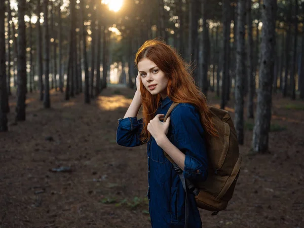 Caminhante mulher ativa com uma mochila na floresta com pinheiros altos na natureza — Fotografia de Stock