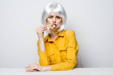 Yemek çubuklarında oturan göz kamaştırıcı kadın çarpık suşi.